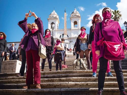 Frauen mit Halstüchern und Kleidungsstücken mit feministischen Aufdrucken stehen auf einer Treppe vor einer Kirche.