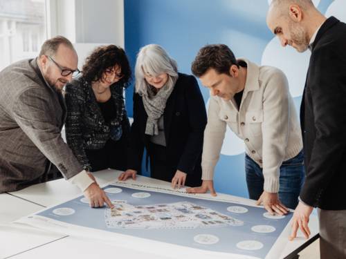 Fünf Personen beugen sich über einen Plan.