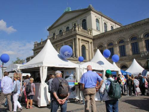 Eine Veranstaltung mit vielen weißen Pavillons auf einem Platz vor einem alten Gebäude: der Oper in Hannover.