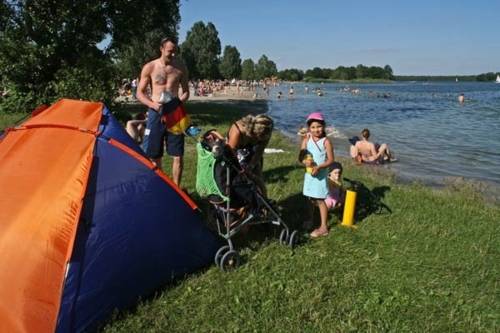 Strandmuschel, Familie mit Kind und Kinderkarre am Altwarmbüchener See, im Hintergrund badende Menschen