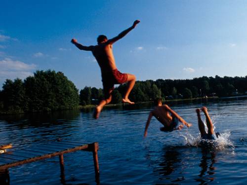 Jungen springen von einem Steg ins Wasser