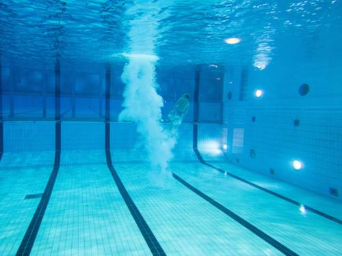 Unterwasseraufnahme einer Person, die ins Schwimmbecken gesprungen ist