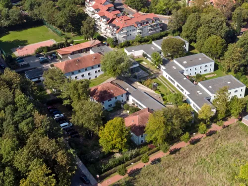 Luftaufnahme eines Gebäudekomplexes, auf dem Außengelände sind Spiel- und Sportgeräte.