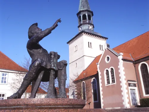 Skulptur "Wickenthies" auf dem Spittaplatz in Burgdorf, dahinter ist die Kirche St. Pankratius.