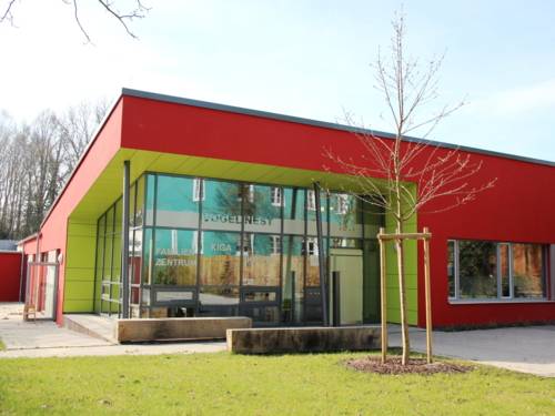 Kubisches Gebäude mit Fassade in den Farben Rot und Grün und großer Glasfläche über Eck.