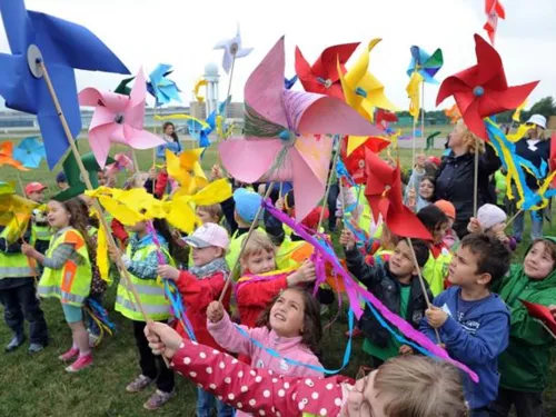 Kinder halten im Freien kleine Propeller in den Wind.
