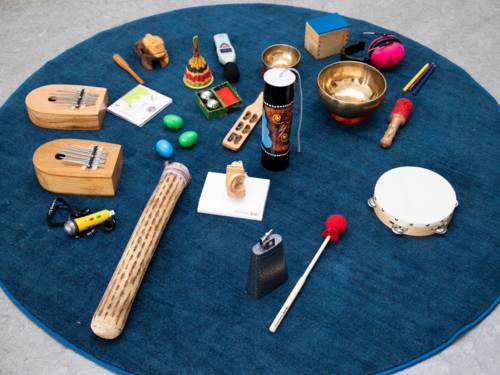 Musikinstrumente, Alltagsgegenstände, Gehörschutz und ein Lautstärkemessgerät liegen auf einem Teppich.