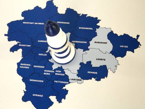 Ein kleiner Leuchtturm steht auf einer Karte der Region Hannover, die Kommunen sind beschriftet. 