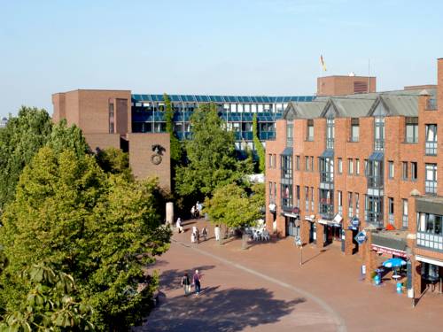 Ein Marktplatz mit Menschen, dahinter der rote Backsteinbau des Rathauses Langenhagen. Rechts ist das City Center Langenhagen zu sehen, links ein großer Baum.