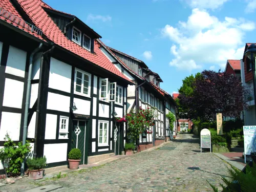 Fachwerkhäuser säumen links und rechts eine mit Natursteinen gepflasterte Gasse.