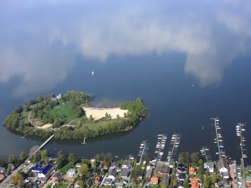 Blick aus einem Flugzeug auf das Ufer des Steinhuder Meeres mit Bootsanlegern und Wald und der Badeinsel.