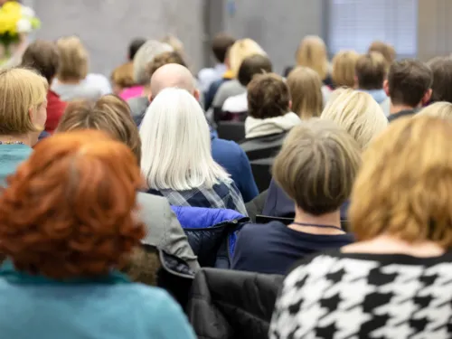 Frauen sitzen auf St&uuml;hlen und folgen dem Programm einer Veranstaltung.