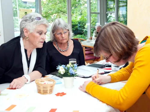 Zwei ältere Damen besprechen sich mit einer jüngeren Frau.