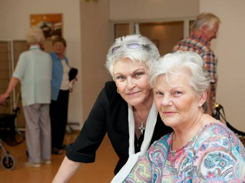 Zwei ältere Frauen halten ihre Köpfe nebeneinander und blicken in die Kamera.