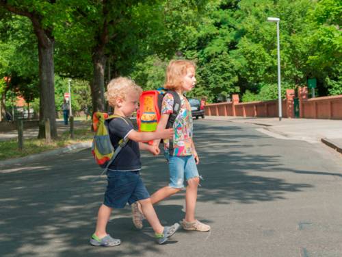 Zwei Kinder, Hand in Hand, überqueren eine Straße