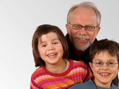 Ein älterer Herr mit Brille, grauem Haar und grauem Vollbart gemeinsam mit einem Mädchen und einem Jungen.