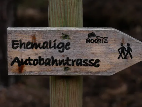 Holzwegweiser mit der Aufschrift "Ehemalige 'Autobahntrasse"