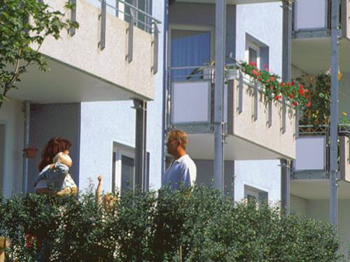 Eine Familie auf dem Balkon eines Mehrfamilienhauses, im Hintergrund weitere Balkone