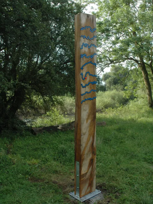 Senkrecht stehender Holzbalken mit blauen Metallwellen und rotem Punkt zur Markierung