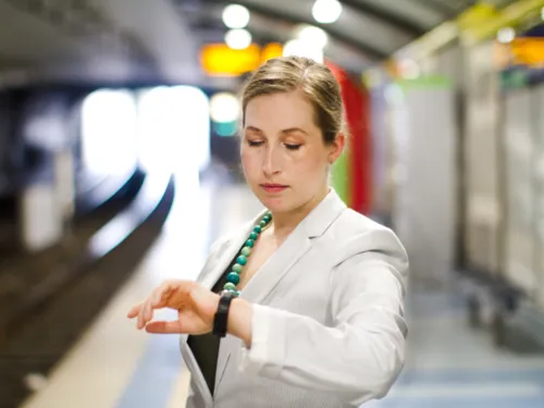 Junge Frau sieht auf ihre Armbanduhr