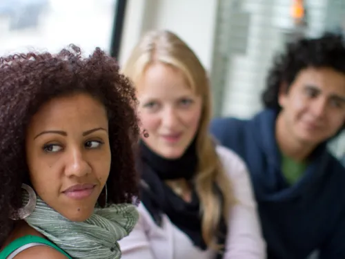 Portraitaufnahme von zwei Frauen und einem Mann. Sie sitzen nebeneinander in der Stadtbahn.