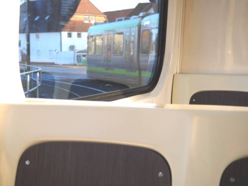 Blick aus dem Fenster einer fahrenden Stadtbahn: Das Schienenfahrzeug fährt um eine Kurve, das Zugvorderteil ist im Fenster zu sehen.