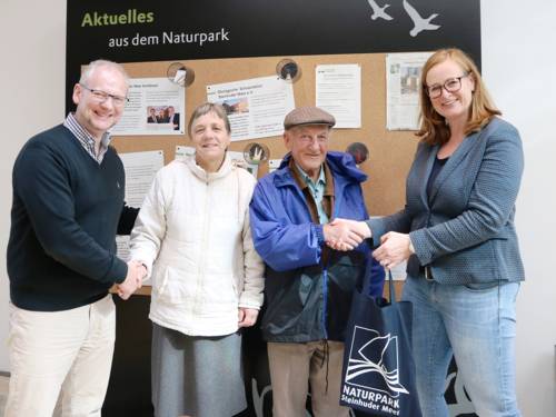 Ein Mann und eine Frau schütteln jeweils die Hände einer weiteren Frau und eines weiteren Mannes.