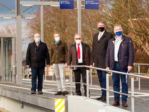 Fünf Herren mit Mund-Nasen-Schutz auf einem Hochbahnsteig in winterlicher Atmosphäre