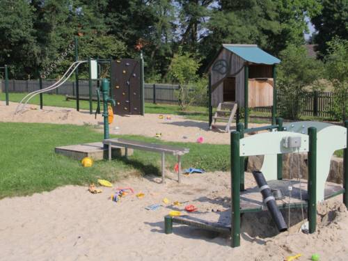 Rutschenturm mit Kletterwand, Wasserpumpe und weitere Spielgeräte auf einem Kinderspielplatz.
