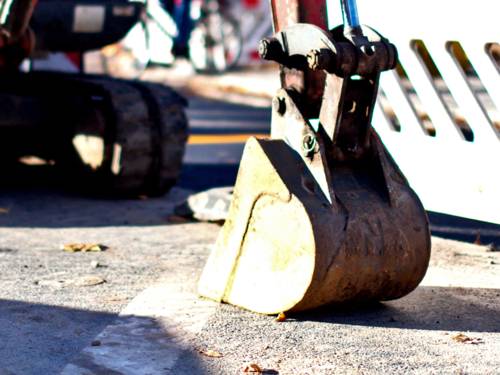 Die Baggerschaufel eines Baggers ruht auf Untergrund.