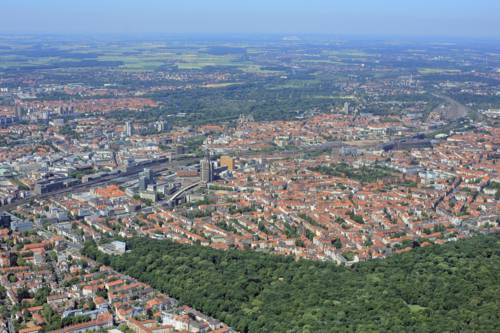 Innenstadt und Stadtwald Eilenriede liegen beieinander, Wohnhäuser, Geschäftsgebäude, Bahngleise und der Hauptbahnhof Hannover sind zu erkennen.