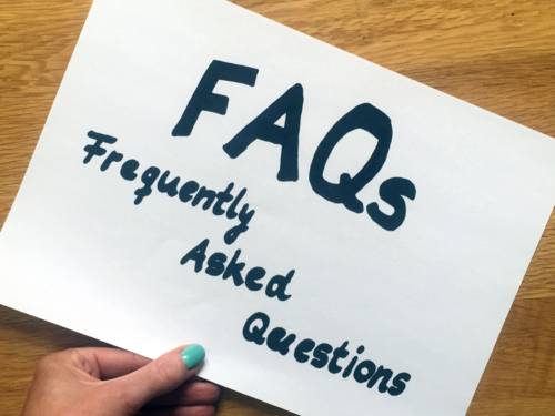Eine Hand und ein Zettel, auf dem "FAQa - Frequently Asked Questions" steht.
