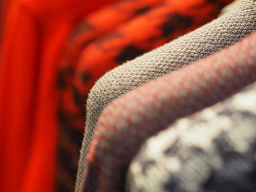 Kleidung auf Bügeln die an einer Kleiderstange hängen.