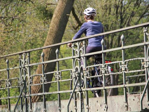 Eine Fahrradfahrerin, die einen Helm trägt, überquert eine Brücke.