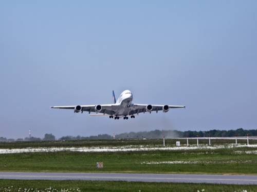 Ein großes Passagierflugzeug startet von einem Flughafen. Das Fahrwerk ist noch ausgefahren, es hebt gerade ab.