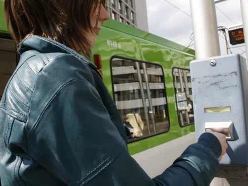 Frau entwertet Fahrkarte an blauem Stempelautomaten.