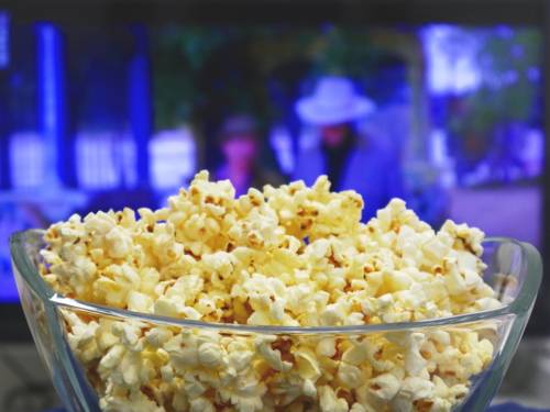 Popcorn in einer Schüssel, im Hintergrund läuft ein Film.
