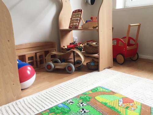 Ein Zimmer mit verschiedenen Spielsachen, unter anderem ein Laufrad, ein Puppenwagen, Wasserbälle.