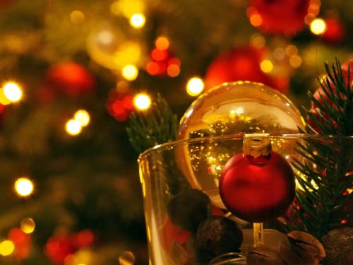 In einer Glaskugel ist ein weihnachtlich geschmückter Tannenbaum, die Glaskugel ist in einem Glas mit Dekomaterial.