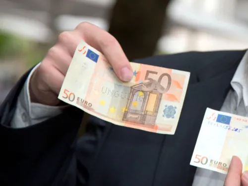 Eine Person hält einen falschen Fünfzigeuroschein mit dem Aufdruck "ungültig".