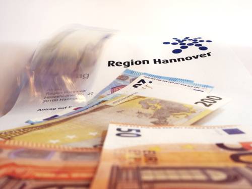 Geldscheine fallen auf ein Antragsformular der Region Hannover.