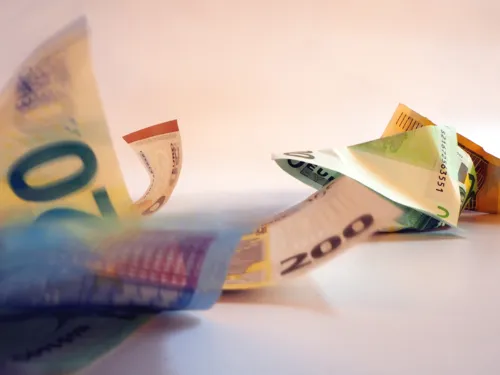 Geldscheine liegen zerknüllt vor einem weißen Hintergrund oder bewegen sich.