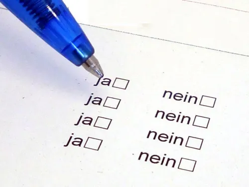 Jemand füllt mit einem Kugelschreiber einen Fragebogen aus.