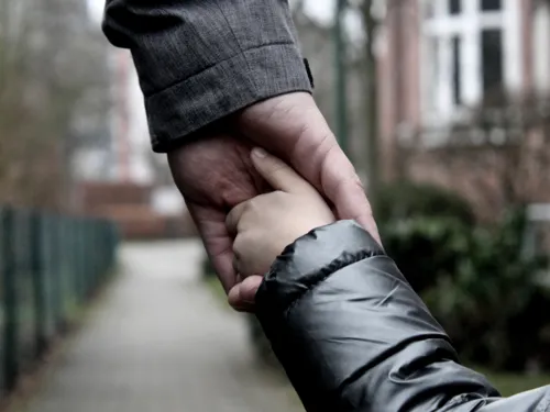 Die Hand eines Erwachsenen greift die Hand eines Kindes.