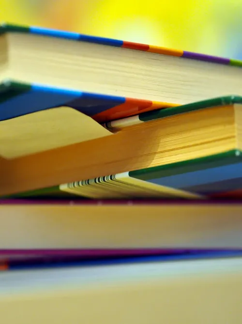 Blick von unten auf einen ungeordneten Stapel von Büchern. Sie scheinen im intensiven Gebraucht, wahrscheinlich zum Nachschlagen und Lernen. Es haftet ein Klebezettel unter einen Buch.