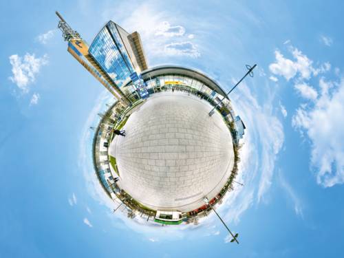Kreative 360-Grad-Ansicht des Messe- und Kongressgel&auml;ndes Hannover im &bdquo;Little Planet&ldquo;-Stil mit Hochhaus und Eingangsbereich.