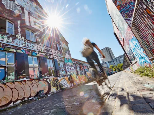 Fahrradfahrer vor einer Wand mit Graffiti.