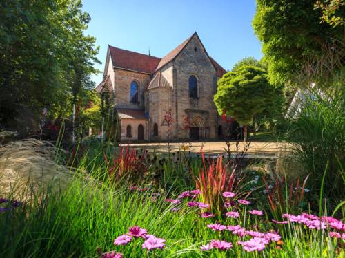 Das Kloster Barsinghausen aus Sandstein, umgeben von einem blühenden Garten mit bunten Blumen und grünen Bäumen.