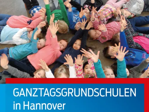 Kinder liegen im Kreis auf dem Boden und strecken ihre Arme dem Betrachter entgegen