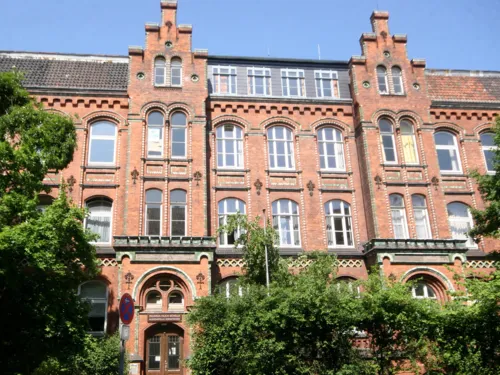 Außenaufnahme eines mehrstöckigen roten historischen Klinkergebäudes mit hohen Fenstern 